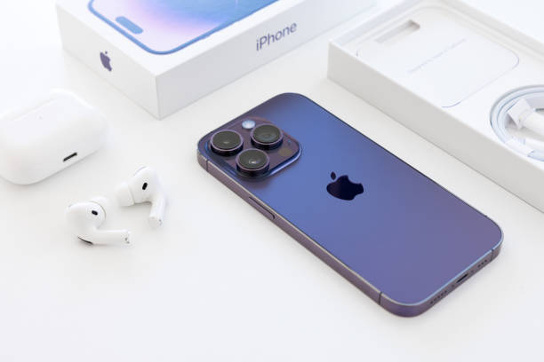 iPhone 14 Pro, it's packaging box and Airpods Pro on white background stock photo