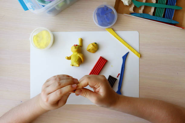istock The child plays and sculpts figures from plasticine. Children's hands with colored plasticine. Children's games and creativity on vacation. Development of fine motor skills of fingers in children 1426154616