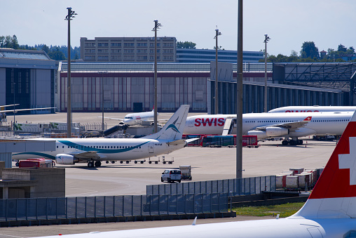 Parked Swiss airplanes at Zürich Airport on a sunny summer day. Photo taken July 15th, 2022, Zurich, Switzerland.