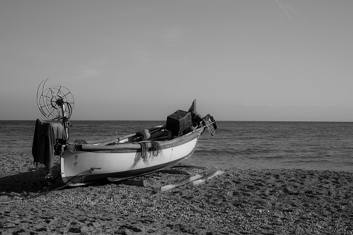 Fishing boat with its equipment on the beach; black and white photo.