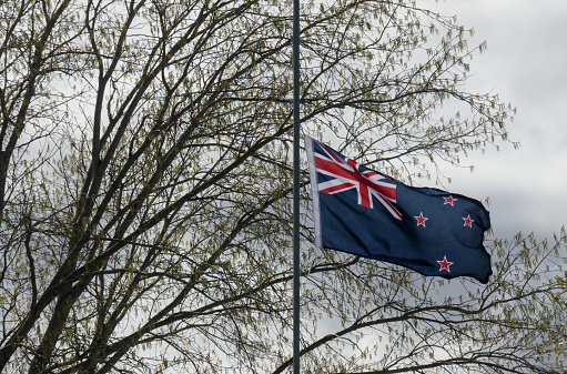 The flag of New Zealand flies at half-mast after the death of Her Majesty Queen Elizabeth II, Queen of New Zealand.  This image was taken outside the War Memorial Community Centre in Tarras, a small town in Central Otago, on an afternoon in early Spring.