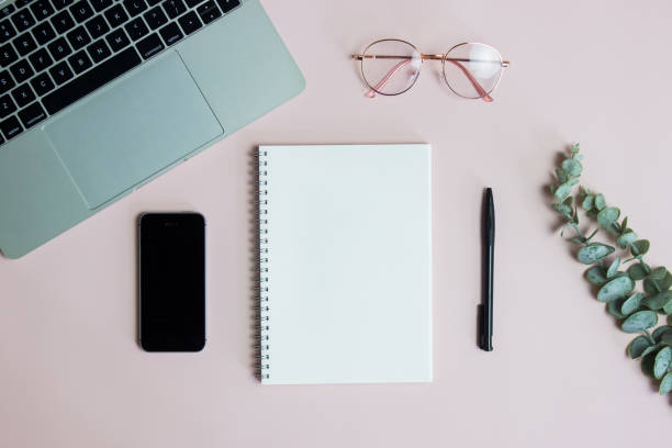 istock Working items with computer, mobile phone, glasses and green leaves on pink background. 1426161660