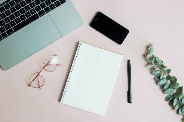 istock Working items with computer, mobile phone, glasses and green leaves on pink background. 1426161665