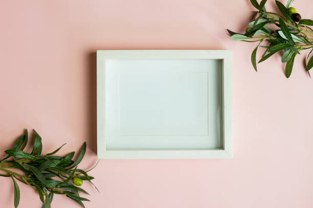 istock A white photo frame with green leaves over the pink background. 1426161685