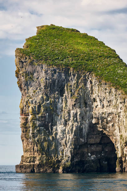 Faroe islands coastline cliff and cave landscape in Vagar island. Faroe islands coastline landscape in Vagar island on sunny day vágar photos stock pictures, royalty-free photos & images