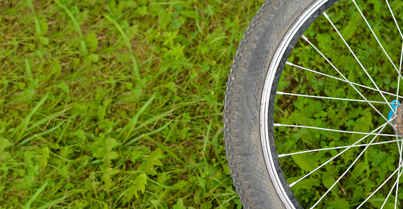 Bicycle wheel on green grass on meadow. Details of a sports bike on a summer background. Sale of spare parts for bicycles.