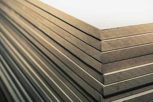 a stack of mdf panels neatly stacked in a cabinetry shop, background blurred with bokeh effect