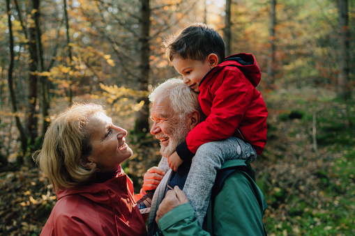 Photo of grandparents and their grandson having a walk through the forest