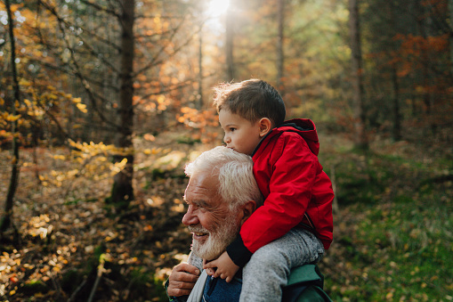 Photo of grandfather and his grandson having a walk through the forest