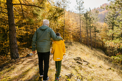 Photo of grandfather and his grandson enjoying a beautiful day in the forest