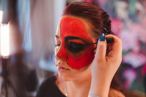 Close-up of a young woman getting her Halloween makeup done by a makeup artist.