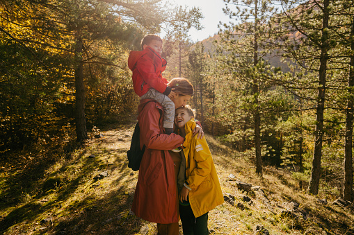 Photo of mother and her sons enjoying a beautiful autumn day in a forest