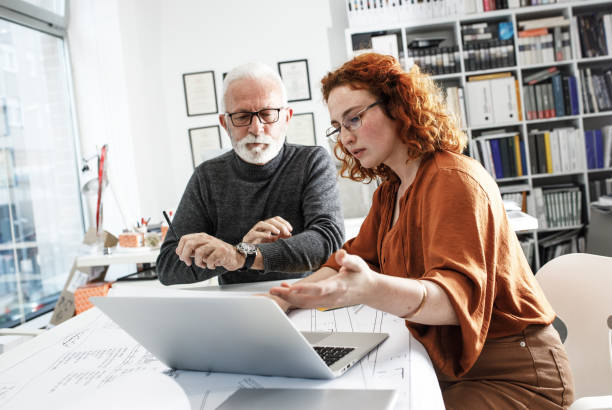 istock A senior designer helps his young female coworker to solve a problem.Design studio. 1426193119