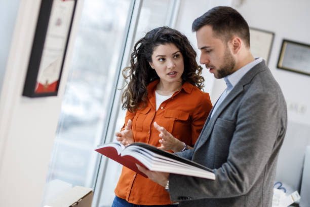 istock Two coworkers standing at the office and examining a new catalog. 1426193252