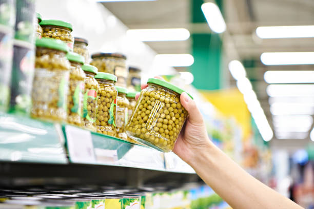 Green peas in glass jar in hands at store Green peas in a glass jar in the hands of a customer in a store grocery shelf cans stock pictures, royalty-free photos & images