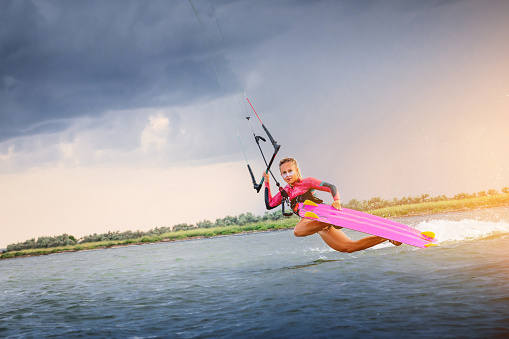 Kite surfer with wakeboard jumps against blue sky. Water extreme sports concept