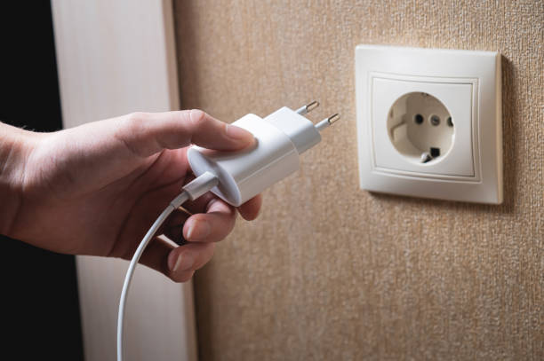 istock A young woman inserts a plug into a socket. A young woman plugs a charger or electrical appliance power cord into a socket. High quality photo 1426196285