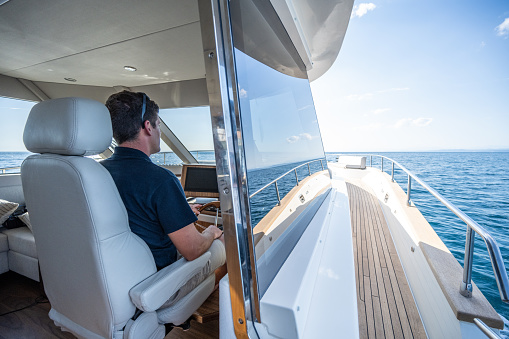 Hand of captain on steering wheel of motor boat in the blue ocean during the fishery day. Success fishing concept. Ocean yacht