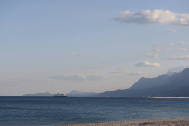 Cargo ship or cruise liner in calm blue mediterranean sea. Traveling in mediterranean sea, view of rocky coast