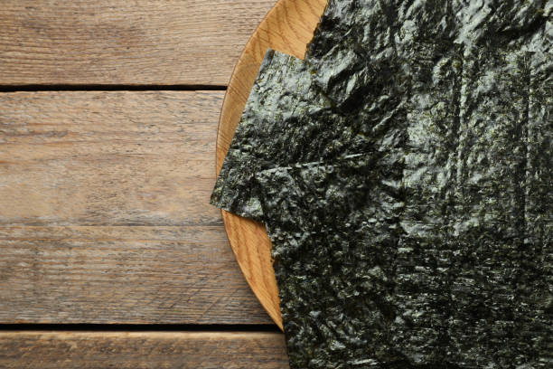 istock Plate with dry nori sheets on wooden table, top view. Space for text 1426206994