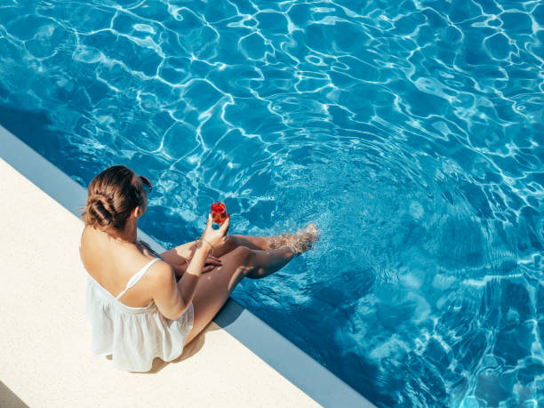 istock Fashionable woman sitting by the pool on the empty deck 1426207143