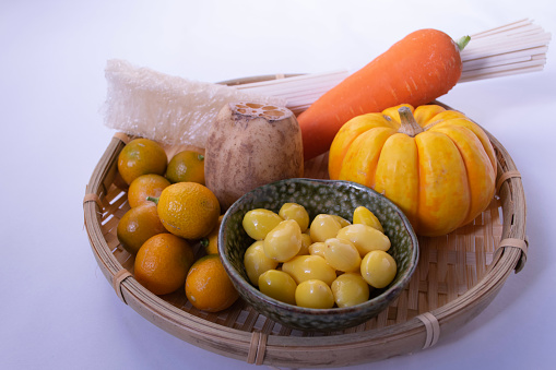 A colander filled with the seven foodstuffs for the winter solstice that are believed to bring good luck: pumpkin, carrot, lotus root, ginkgo nut, kumquat, kanten, and udon.