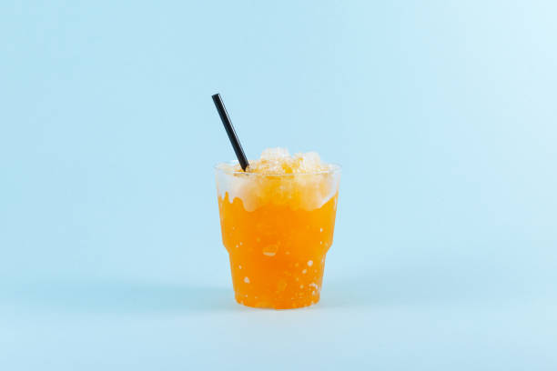 istock Refreshing Slushie drink. Orange Granizado in disposable plastic take away cup on blue background. Sweet citrus Shaved ice. Selective focus, copy space 1426214310
