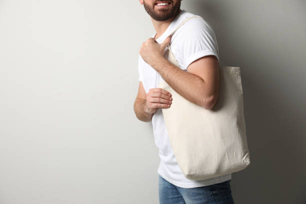 istock Happy man with eco bag on light background, closeup. Space for text 1426214662