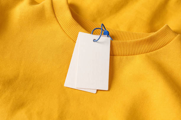 istock Blank white tags on yellow sweatshirt, top view. Space for text 1426215311