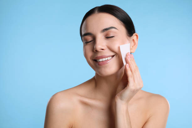 istock Beautiful woman using mattifying wipe on light blue background 1426216468