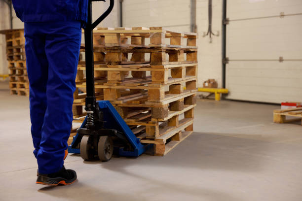 istock Worker moving wooden pallets with manual forklift in warehouse, closeup 1426218185