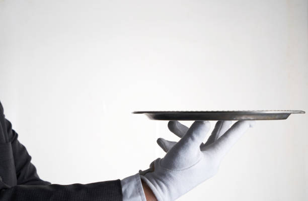istock Elegant waiter hand in white glove holding an empty plate with white background. 1426220714