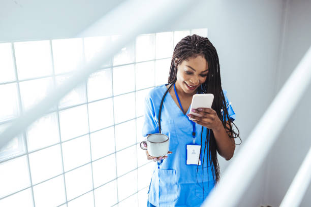 Nurse Using Her Mobile Phone While Taking a Break. stock photo
