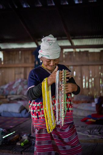 An older Hmong Hilltribe woman happy inside village home in Chiang Mai, Thailand with traditional clothing.