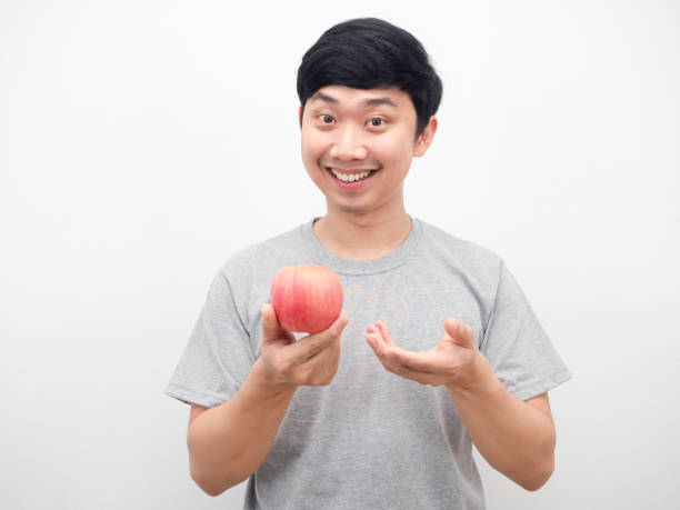 istock Handsome man showing red apple in hand with happy smiling 1426226435