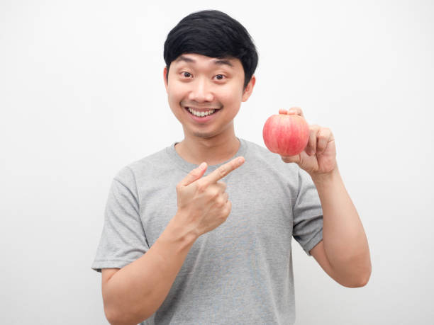 istock Man smiling and point at red apple in hand portrait 1426226481