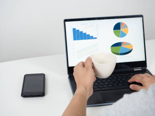 istock Man hand holding coffee cup and using laptop on the table with mobile phone 1426226763