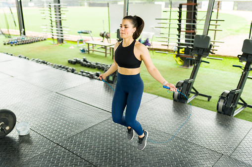 Active young woman doing her cardio workout at the gym and jumping rope