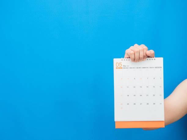 istock Man hand holding calendar 2022 on blue background 1426229810