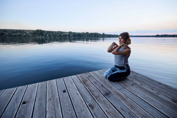 istock Yogi woman meditates and does breathing exercises while sitting on the dock. 1426230505