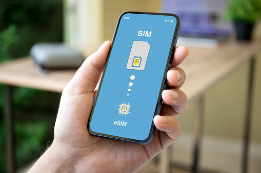 man hand holding phone with Sim card replacement on eSim on screen in office