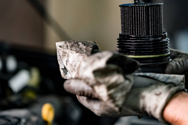 Hands of a repairman holding dirty car oil filter stock photo