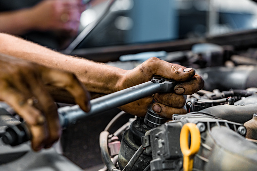 Close up photo of auto mechanic repairing car engine in car service