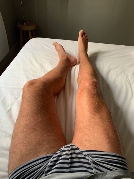 Tanned bare legs in bed. stock photo