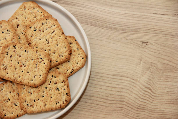dry square diet crackers with black cumin seeds and quinoa on  decorative glass plate