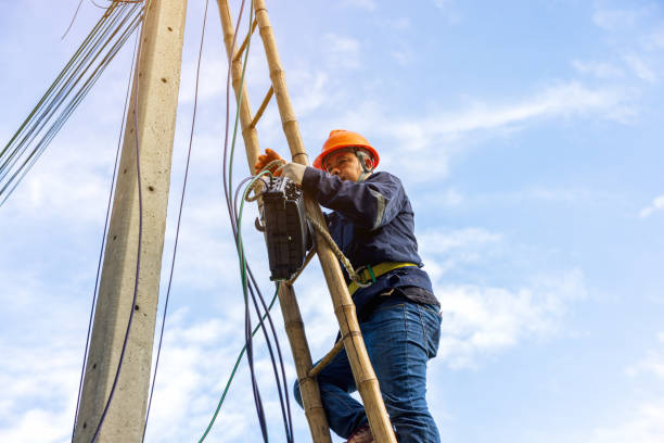 istock A telecoms worker is shown working from a utility pole ladder while wearing high visibility personal safety clothing, PPE, and a hard hat. 1426239841