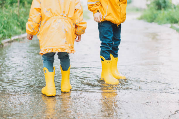 istock Children in yellow rubber boots walk through puddles 1426239983