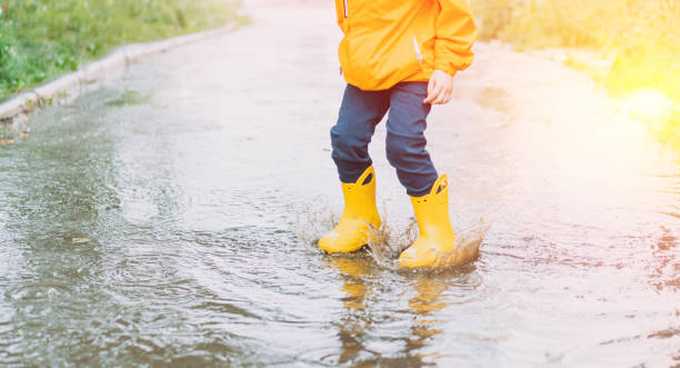 istock Child in yellow rubber boots jumping through puddles 1426239985