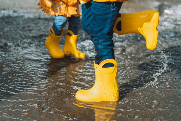 istock Children in yellow rubber boots jumping in puddles 1426240003