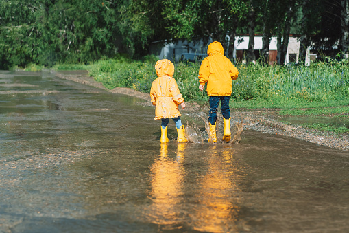 Children in yellow rubber boots walk through puddles.